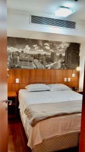 聖保羅的住宿－Flat em Hotel na Bela Cintra próximo à Paulista e Consolação，卧室配有一张大床,墙上挂有绘画作品