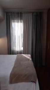 a bedroom with a bed and a window with curtains at Flat em Hotel na Bela Cintra próximo à Paulista e Consolação in Sao Paulo