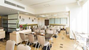 um restaurante com cadeiras brancas e mesas num quarto em Hearton Hotel Higashi-Shinagawa em Tóquio