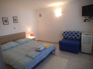 a bedroom with a bed and a blue chair at Blue View Apartments in Trogir