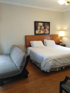 una habitación de hotel con 2 camas y una silla en Lake view resort style suite big room, en Tottenham