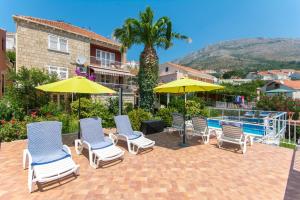 - un groupe de chaises longues et de parasols à côté de la piscine dans l'établissement Apartments with a swimming pool Mlini, Dubrovnik - 9009, à Mlini