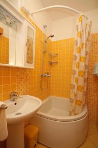 La salle de bains est pourvue d'une baignoire, d'un lavabo et d'une douche. dans l'établissement Apartments with a swimming pool Mlini, Dubrovnik - 9009, à Mlini
