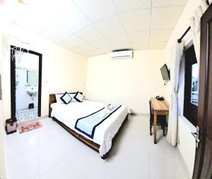1 dormitorio con cama, escritorio y espejo en Blue Beach Homestay, en Hoi An