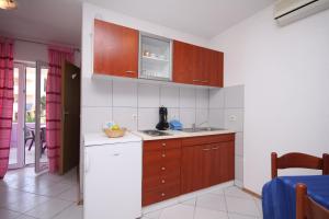 eine Küche mit Holzschränken und einem weißen Kühlschrank in der Unterkunft Apartments with a parking space Stari Grad, Hvar - 8752 in Stari Grad
