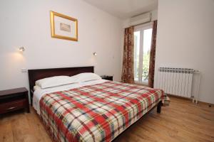 1 dormitorio con 1 cama con manta a cuadros y ventana en Apartments and rooms with parking space Mlini, Dubrovnik - 8994, en Mlini