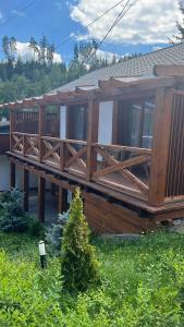 a house with a wooden deck in the yard at Cabana B2 langa strandul Banffy in Topliţa