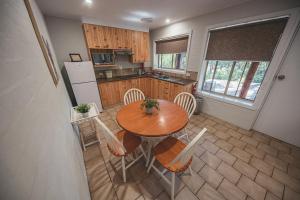 a kitchen with a table, chairs, and a refrigerator at Kianinny Bush Cottages in Tathra