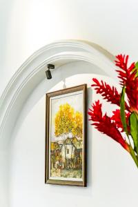 a framed painting of a tree on a wall with red flowers at 9 Hostel and Suites in Ho Chi Minh City