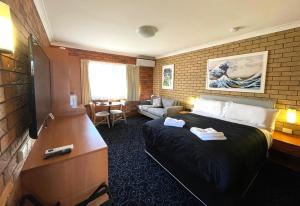 GuyraShiralee Motel Guyra的一间带床和客厅的酒店房间