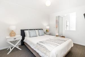 um quarto branco com uma cama e uma mesa de cabeceira em Fairway Views em Mollymook