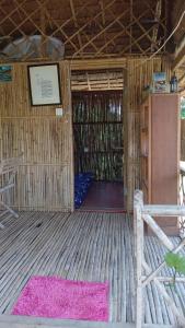 an open door of a straw hut with a pink rug at Battambang Eco Stay in Phumĭ Ândong Pring