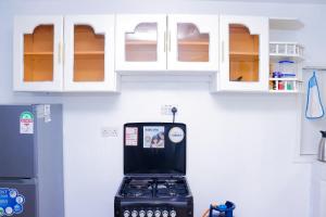 a kitchen with a refrigerator and white cabinets at Homely Homes in Nairobi +3 photos
