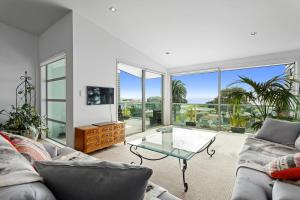 a living room with a couch and a glass table at Pohutukawa Paradise - Ōhope Holiday Apartment in Ohope Beach