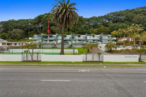 a street view of a building with a palm tree at Pohutukawa Paradise - Ōhope Holiday Apartment in Ohope Beach