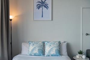 a bedroom with a bed with a palm tree picture on the wall at Ocean View Apartment 49 in Airlie Beach