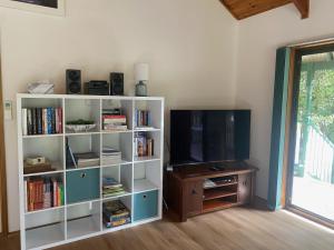 een woonkamer met een tv en een boekenplank bij Tranquil on Churchill Linen included Pet friendly Wifi in Inverloch
