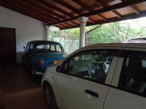 een witte auto en een blauwe auto geparkeerd in een garage bij Green Villa Home in Anuradhapura