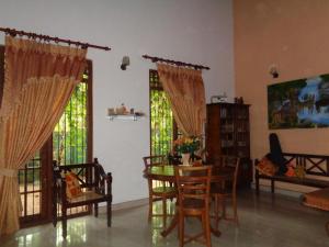 een woonkamer met een tafel, stoelen en ramen bij Green Villa Home in Anuradhapura