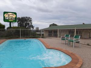 a swimming pool with two chairs and a motel sign at Country Rose Motel Warwick in Warwick