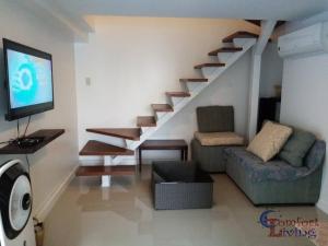 a living room with a staircase with a couch and a tv at 2 BR loft-type condo Fort Victoria in Manila