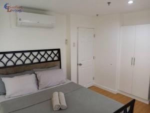 a bedroom with a large bed with two towels on it at 2 BR loft-type condo Fort Victoria in Manila