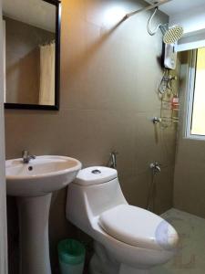 a bathroom with a sink and a toilet and a mirror at 2 BR loft-type condo Fort Victoria in Manila