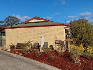 a building with a bench and flowers in a yard at Country Rose Motel Warwick in Warwick