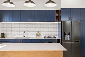 a kitchen with blue cabinets and a stainless steel refrigerator at The Stables at the Hill in Newcastle