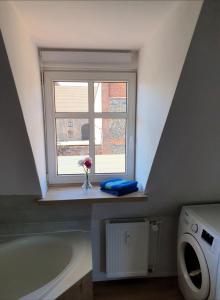 a bathroom with a window and a vase of flowers on a counter at Gemütliche Dachwohnung mit kleiner oder großer Dachterrasse nebeneinander in Wolmirstedt