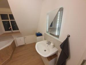 ein weißes Badezimmer mit einem Waschbecken und einem Spiegel in der Unterkunft Gemütliche Dachwohnung mit kleiner oder großer Dachterrasse nebeneinander in Wolmirstedt