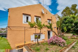 a yellow house with white windows and flowers at Holiday Home Lina Cipollina in Mali Lošinj