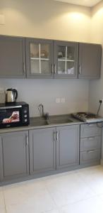 uma cozinha com armários cinzentos e um micro-ondas em مزرعة الكرم الحاتمي em Al Shafa