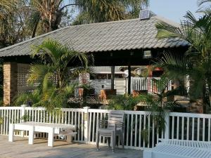 a white fence with a table and chairs in front of a house at Peace Cottages Uvongo. in Uvongo Beach