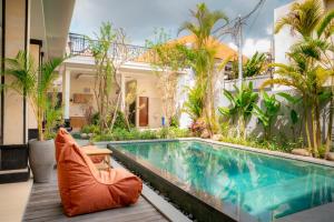 チャングーにあるThe Manggar Guesthouseの家の隣にあるスイミングプール(椅子付)