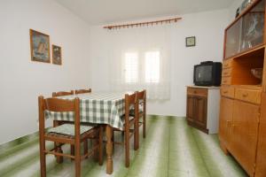 a dining room with a table and chairs and a tv at Apartments with a parking space Komiza, Vis - 8866 in Komiža