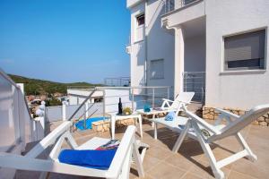 einen Balkon mit Stühlen und Tischen auf einem Gebäude in der Unterkunft Luxury villa with a swimming pool Vis - 8922 in Vis