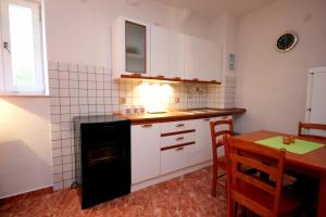 a kitchen with white cabinets and a table and a stove at Apartments by the sea Vis - 8932 in Vis