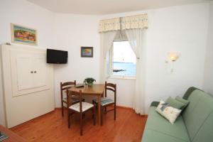 d'un salon avec une table, des chaises et une fenêtre. dans l'établissement Apartments and rooms by the sea Komiza, Vis - 8910, à Komiža