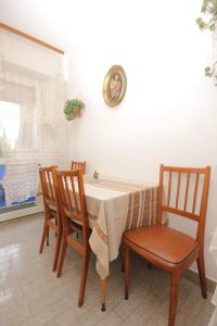 einem Esstisch mit 3 Stühlen und einer Uhr an der Wand in der Unterkunft Apartments by the sea Vis - 8906 in Vis