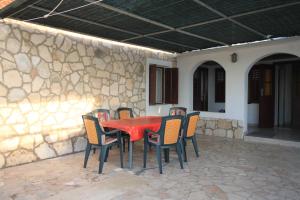 a red table and chairs on a patio at Apartments by the sea Milna, Vis - 8913 in Vis