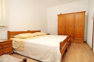 a bedroom with a large bed and a wooden cabinet at Apartments by the sea Brna - Vinacac, Korcula - 9152 in Smokvica
