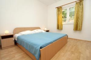 a bedroom with a bed with a blue blanket and a window at Apartments by the sea Molunat, Dubrovnik - 8956 in Molunat