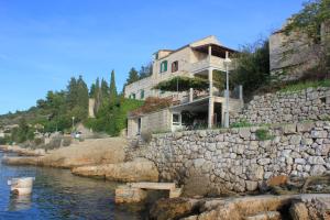 a house on top of a rock wall next to the water at Apartments by the sea Vis - 8930 in Vis