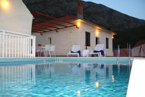 a villa with a swimming pool in front of a house at Holiday house with a swimming pool Dubravka, Dubrovnik - 9101 in Gruda +13 photos