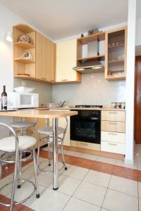 a kitchen with wooden cabinets and a table with stools at Apartments with a parking space Dubrovnik - 9026 in Dubrovnik