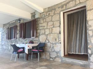 stół i krzesła siedzące obok kamiennej ściany w obiekcie Apartments by the sea Cove Mala Pogorila, Hvar - 8952 w mieście Bogomolje