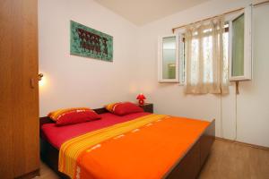 a bedroom with a bed with orange sheets and a window at Secluded fisherman's cottage Cove Spiliska, Korcula - 9142 in Vela Luka
