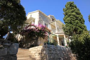 Apartments by the sea Brna, Korcula - 9139 في برنا: منزل أبيض وبه زهور على جدار حجري