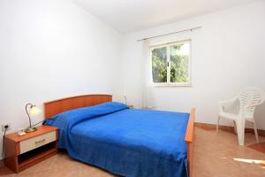 a bedroom with a bed and a chair and a window at Apartments by the sea Brna, Korcula - 9139 in Brna